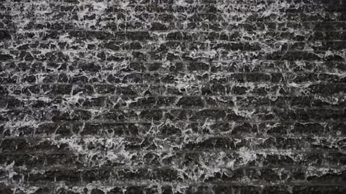 Water Flows Down a Textured Gray Wall