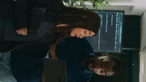 Vídeo vertical: dois codificadores de software analisando o código-fonte em busca de erros no laptop