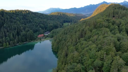 Flug bei Sonnenuntergang über den Bergsee Alatsee, Deutschland, Wilde Natur und Kiefernwald