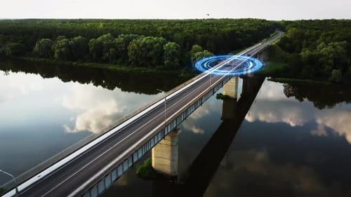 Aerial view of an autonomous vehicle with autopilot travelling on a bridge over a river.