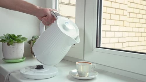 Pouring Hot Water into Cup from White Kettle