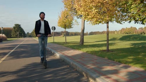 Happy Bearded Man on Electric Scooter Riding Admiring Beauty of Autumn Nature
