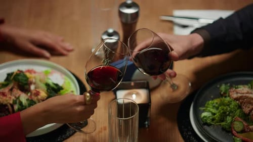 Unrecognizable lovers celebrate valentines day clinking wine glasses at restaurant