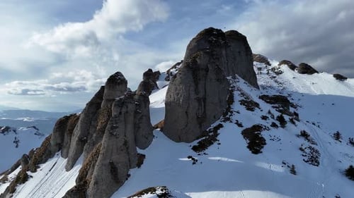 Montañas de Ciucas cubiertas de nieve bajo un cielo azul, con picos escarpados y un sentido de aventura, vista aérea