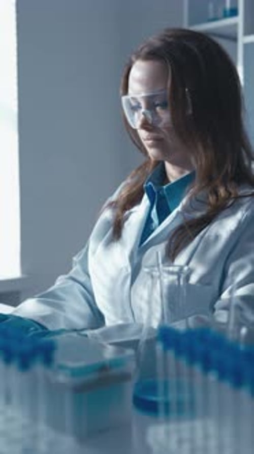 Woman Working With Microscope and Computer in Lab
