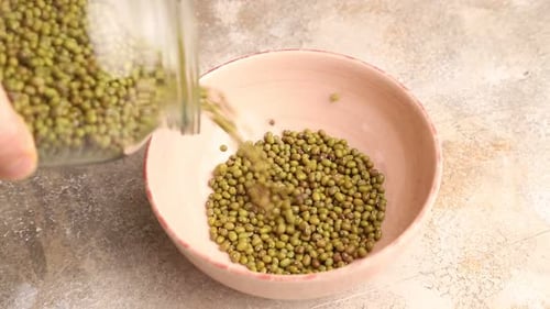 los frijoles mungo se vierten en un recipiente de cerámica sobre un fondo de hormigón marrón