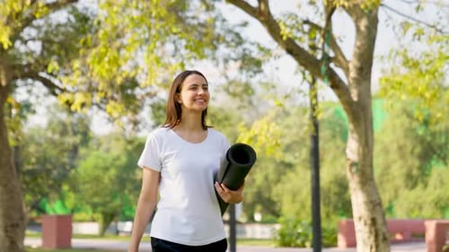 Woman Walking With Yoga Mat in Green Park