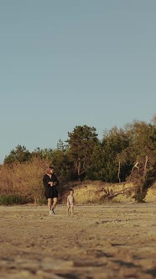 A Mother Enjoying a Leisurely Walk Along the Beach with Her Daughter During a Stunning Sunset