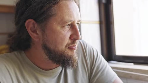 Thoughtful Man with Dreadlocks Eating Meal By the Window