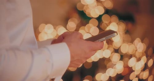 Man Using Cellphone at Illuminated Home During Christmas