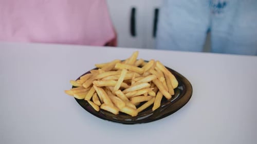 Friends Sharing Golden French Fries at Table