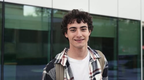 Smiling Young Man with Curly Hair in Urban Setting