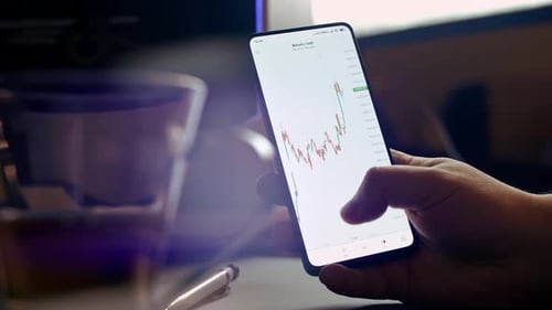 графики криптовалют на экране мобильного телефона