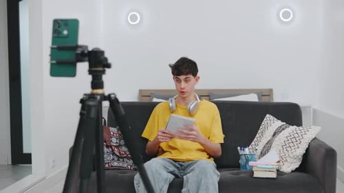 Young Adult Vlogging with Phone on Tripod Indoors