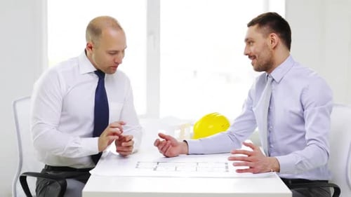 Smiling businessmen review blueprints in the office for a new real estate project