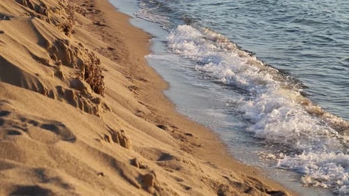 Light waves and sandy beach at sunset
