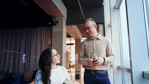 Female and male colleagues cheerfully talk in the office.