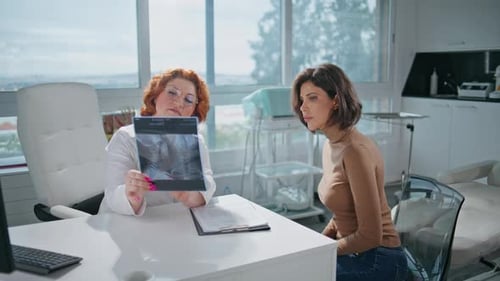 Woman Radiologist Showing Xray to Focused Patient in Medicare Office Closeup