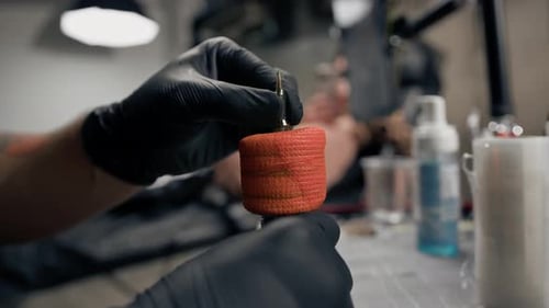 Person Inserts Needle into Tattoo Machine