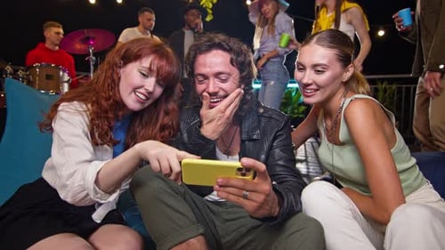 Friends watching phone together at a party at night