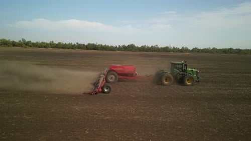 Green tractor seeding wheat on the field