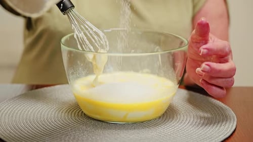 Mujer que vierte azúcar en huevos para hacer dulces navideños caseros en cámara lenta