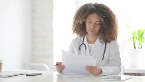 Afrcian Doctor Reading Documents while Sitting in Clinic