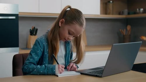 Girl Doing Homework on Laptop in Kitchen