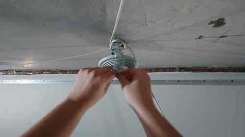 Hands Connecting Wires While Installing Ceiling Lamp Base