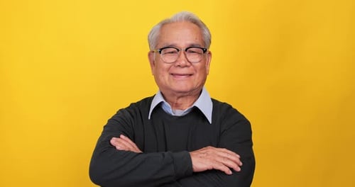 Close up, portrait of older man smiling and looking at the camera. Isolated on yellow background
