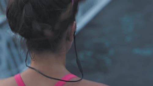 Fit woman running and jogging on a bridge in a city outdoors from behind