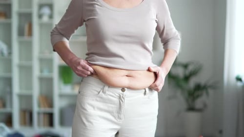 Woman Holds Stomach in an Indoor Setting