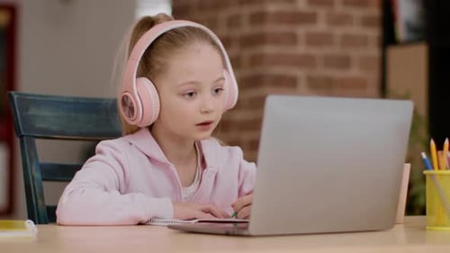 Girl Learning Online and Taking Notes at Desk