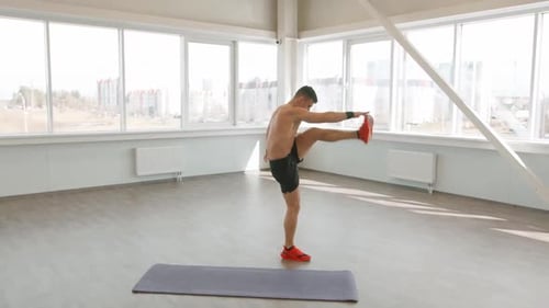 Muscular Man Training in Gym with Lunges and Kicks