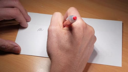 Man writes an address on a white envelope. CLOSE UP SHOT.
