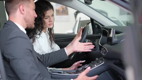 Concentrated Young Female Customer Sits Behind the Wheel of a New Car Takes a Test Drive