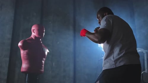 Fitness Workout in Gym Strong African Man Fighter Training Punches with Hitting Punching Bag
