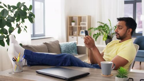 Man Relaxing with Phone Indoors at Desk