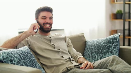 Man Relaxing on Couch Talking on Smartphone
