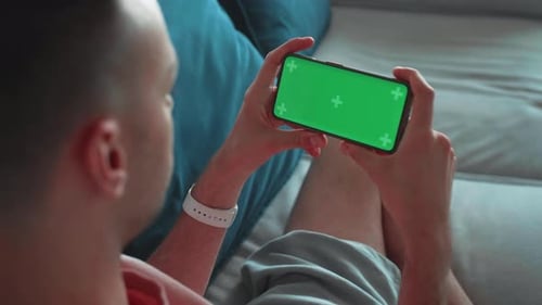 Shoulder Shot of a Man's Hand Holding Horizontal Green Mockup Screen Smartphone Modern Mobile Phone