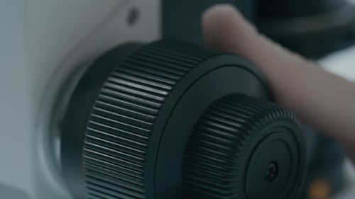 Adjusting Focus Knob on Microscope in Lab