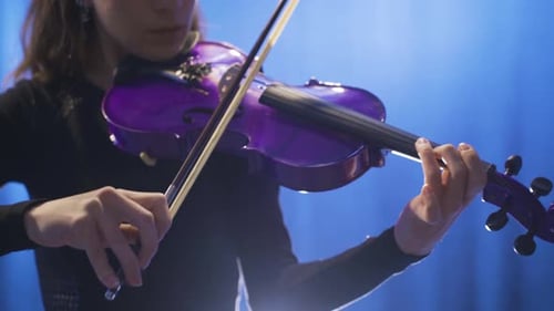 Close-up of young female musician playing violin on stage and her violin.