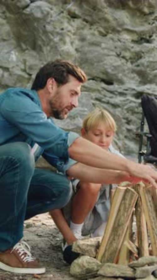 Father and Son Sitting Together Make Fire at Picnic Making Firewood Mother and Daughter Having Fun