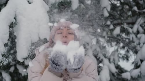 Woman Blowing Snow in Snowy Winter Forest