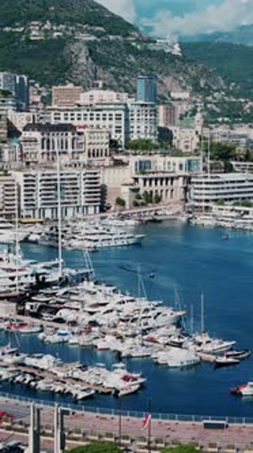 Aerial view of boats docked in the Monaco Marina with the skyline of the city on the background