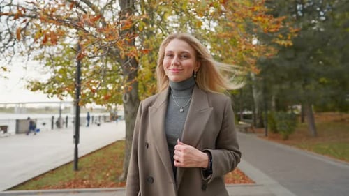 Attractive Business Woman with Blond Hair Walks in Autumn Park on Cloudy Day