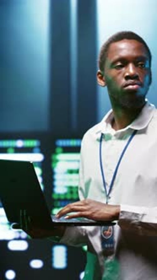 Focused Young Man Working on Laptop in Data Center