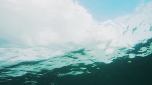 Underwater rearview of ocean wave building and crashing with whitewash