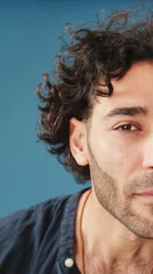 Close-up, man looking at camera looking for something isolated on blue background in studio