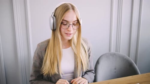 Professional Woman Engaging in a Video Call While Wearing Headphones and a Blazer in a Modern Office